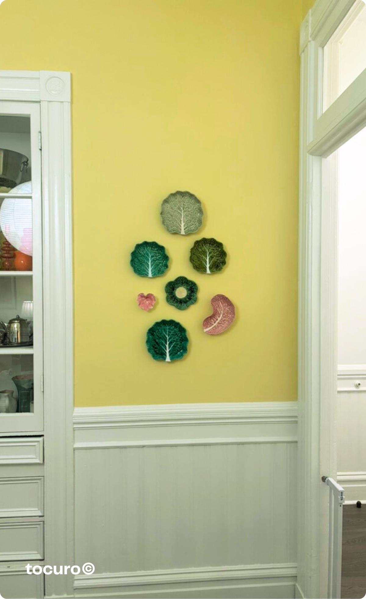 Bordallo Pinheiro cabbage plates styled in my dining room alongside other ceramics—proof that when you buy what you love, you'll always find a place for it, even if it doesn't match what you already own